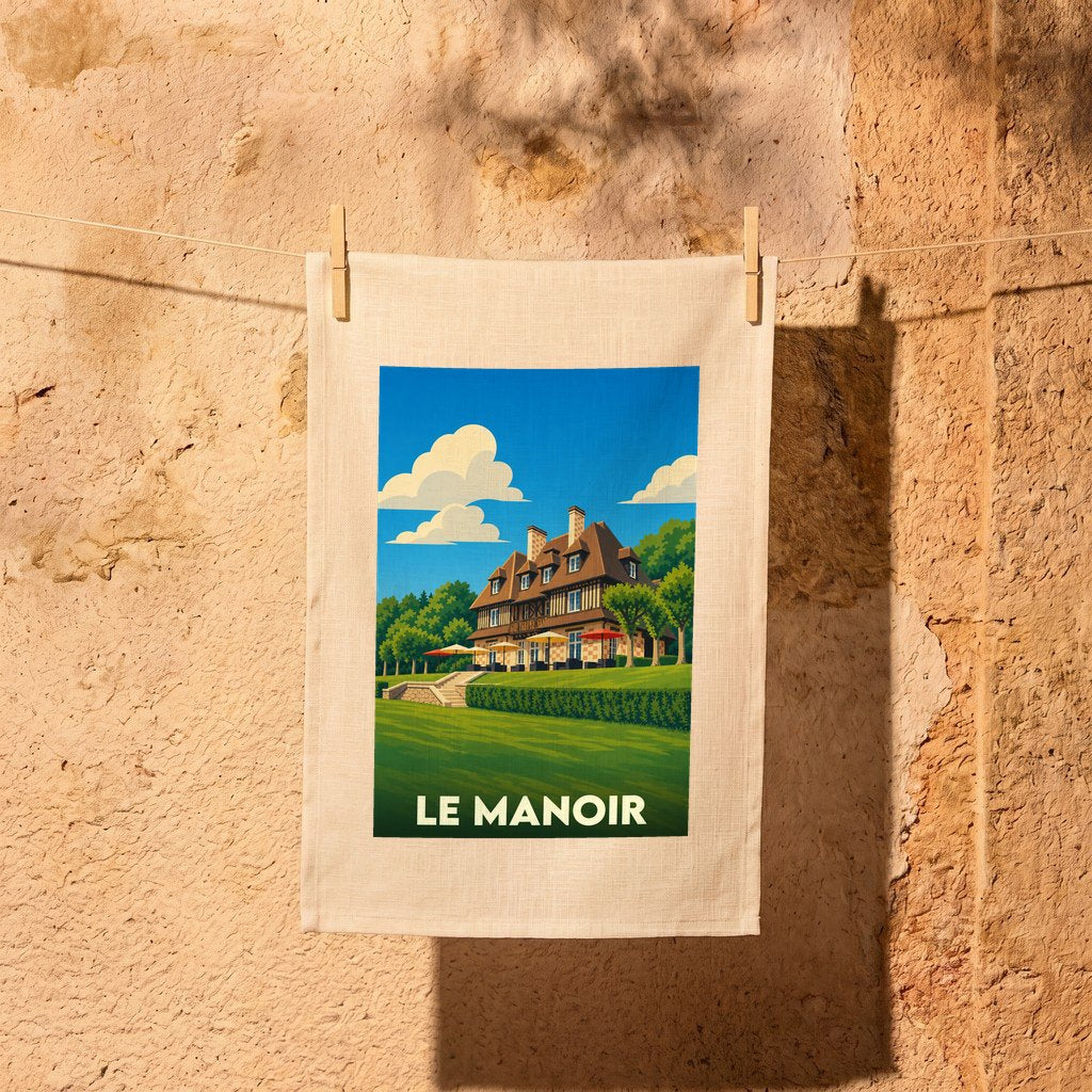 Torchon souvenir de la ville de Le Manoir avec une illustration stylisée d'une demeure normande.