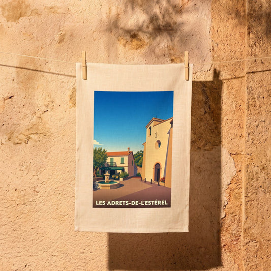 Torchon souvenir de la ville de Les Adrets-de-l'Estérel avec une illustration stylisée d'une place provençale.