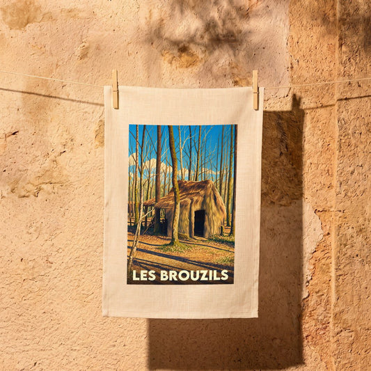 Torchon souvenir de la ville de Les Brouzils illustré par une cabane en forêt sous un ciel bleu.