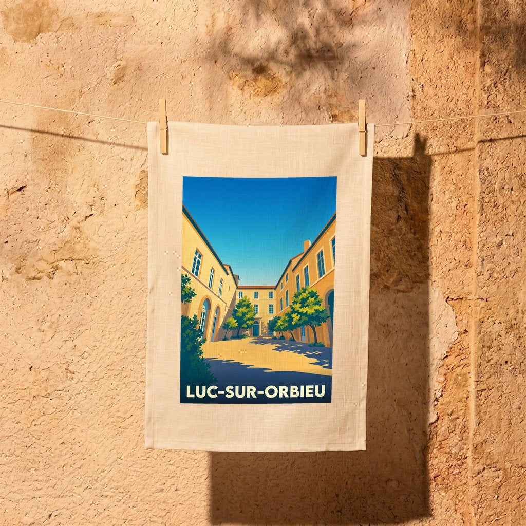 Torchon souvenir de la ville de Luc-sur-Orbieu avec une illustration stylisée d'une place ensoleillée.