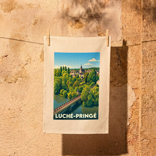 Torchon souvenir de la ville de Luché-Pringé avec une illustration stylisée représentant un pont et un clocher entourés de verdure.