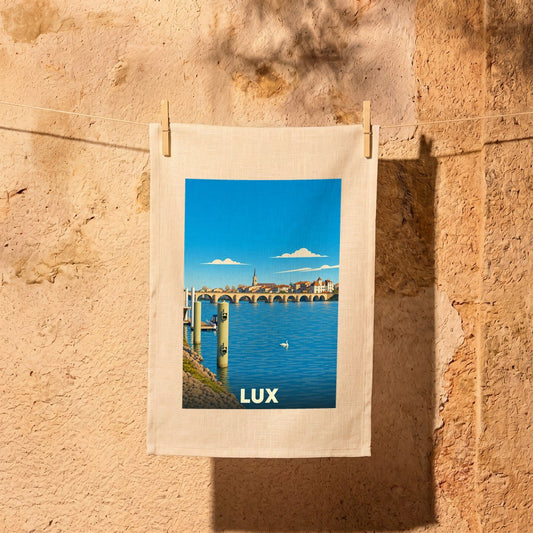 Torchon souvenir de la ville de Lux avec une illustration stylisée d'un pont sur un fleuve.