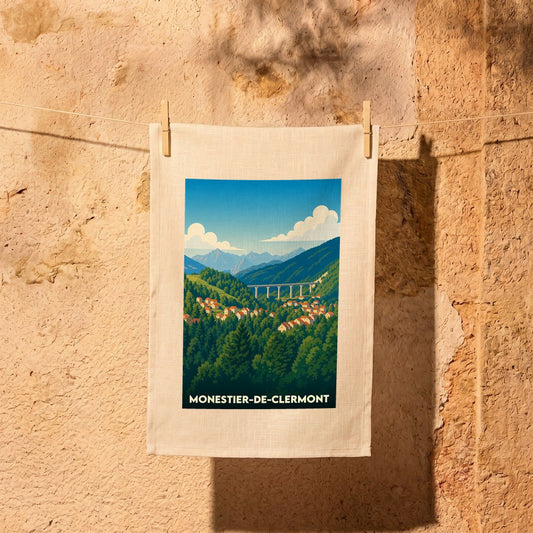 Torchon souvenir de la ville de Monestier-de-Clermont avec une illustration stylisée d'un paysage de montagne.