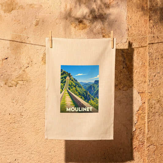 Torchon souvenir de la ville de Moulinet avec une illustration stylisée d'un chemin de montagne.