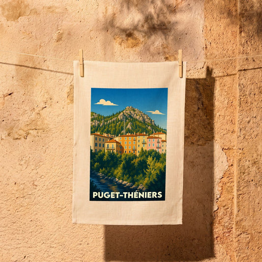 Torchon souvenir de la ville de Puget-Théniers orné d'une illustration stylisée de ses maisons colorées au pied des montagnes.