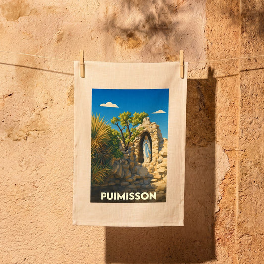Torchon souvenir de la ville de Puimisson avec une illustration stylisée représentant une vierge dans sa grotte.
