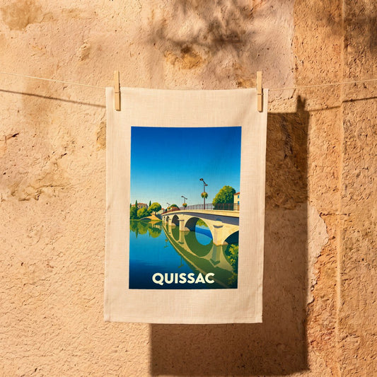Torchon souvenir de la ville de Quissac illustré d'un pont se reflétant dans l'eau.
