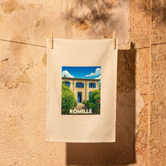 Torchon souvenir de la ville de Romillé avec une illustration stylisée d'une maison en pierre aux volets bleus.