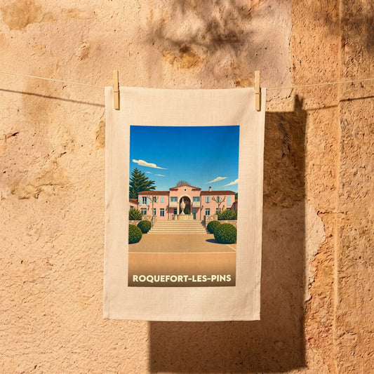 Torchon souvenir de la ville de Roquefort-les-Pins avec une illustration stylisée d'une villa provençale.