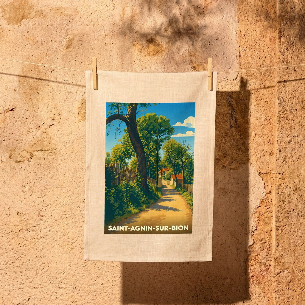 Torchon souvenir de la ville de Saint-Agnin-sur-Bion avec une illustration stylisée d'un chemin de campagne ensoleillé.