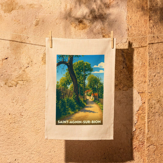 Torchon souvenir de la ville de Saint-Agnin-sur-Bion avec une illustration stylisée d'un chemin de campagne ensoleillé.