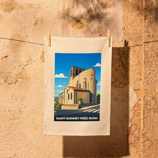 Torchon souvenir de Saint-Bonnet-près-Riom illustré d'une vue stylisée de son église sous un ciel bleu.