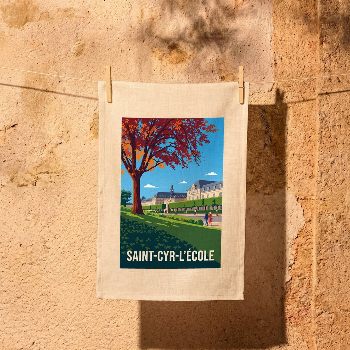 Torchon souvenir de la ville de Saint-Cyr-l'École avec une illustration stylisée de ses bâtiments historiques sous un arbre d'automne.