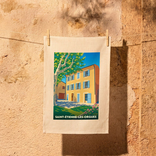Torchon souvenir de la ville de Saint-Étienne-les-Orgues avec une illustration stylisée d'une maison provençale.