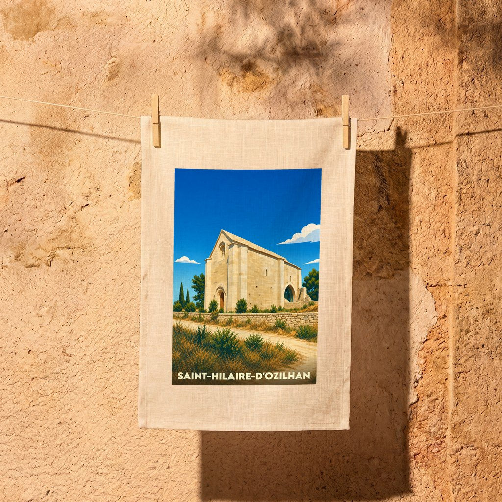 Torchon souvenir de Saint-Hilaire-d'Ozilhan orné d'une illustration stylisée de sa chapelle sous un ciel bleu.