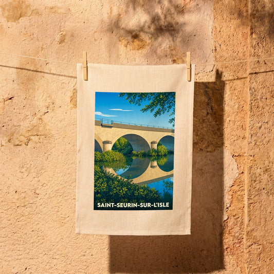 Torchon souvenir de la ville de Saint-Seurin-sur-l'Isle avec une illustration stylisée d'un pont de pierre se reflétant dans l'eau.