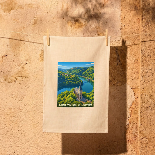 Torchon souvenir de la ville de Saint-Victor-et-Melvieu avec une illustration stylisée d'un paysage de rivière et d'église.