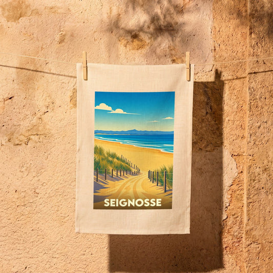 Torchon souvenir de la ville de Seignosse avec une illustration stylisée d'un chemin dunaire menant à l'océan.