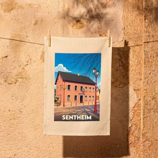 Torchon souvenir de la ville de Sentheim illustré d'un dessin stylisé de sa mairie sous un ciel bleu.