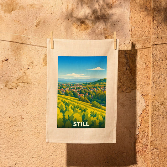 Torchon souvenir de la ville de Still avec une illustration stylisée de son paysage vallonné.