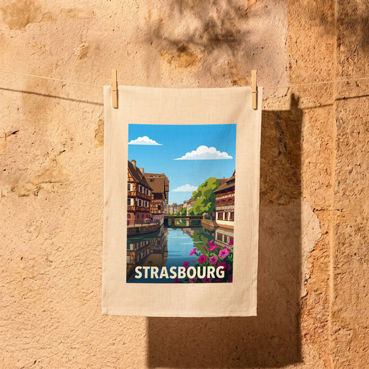 Torchon souvenir de la ville de Strasbourg avec une illustration stylisée de maisons à colombages au bord de l'eau.