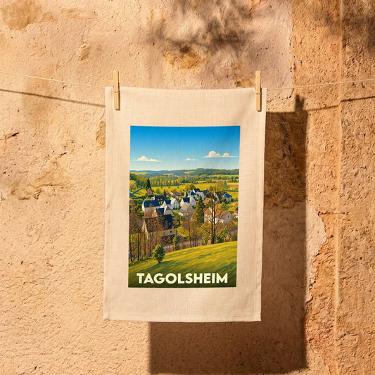 Torchon souvenir de la ville de Tagolsheim avec une illustration stylisée d'un paysage de campagne.