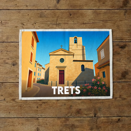 Torchon souvenir de la ville de Trets illustrant son église provençale sous un ciel bleu azur.