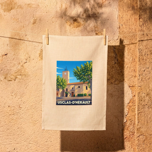 Torchon souvenir de la ville d'Usclas-d'Hérault orné d'une illustration stylisée de son église et de sa tour de l'horloge.
