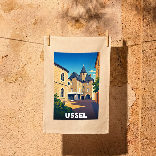 Torchon souvenir de la ville d'Ussel illustré d'un paysage urbain stylisé.