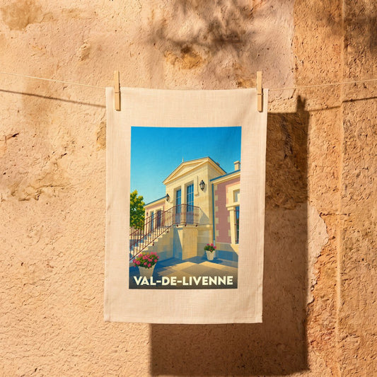 Torchon souvenir de la ville de Val-de-Livenne avec une illustration stylisée d'un bâtiment en pierre sous un ciel bleu.