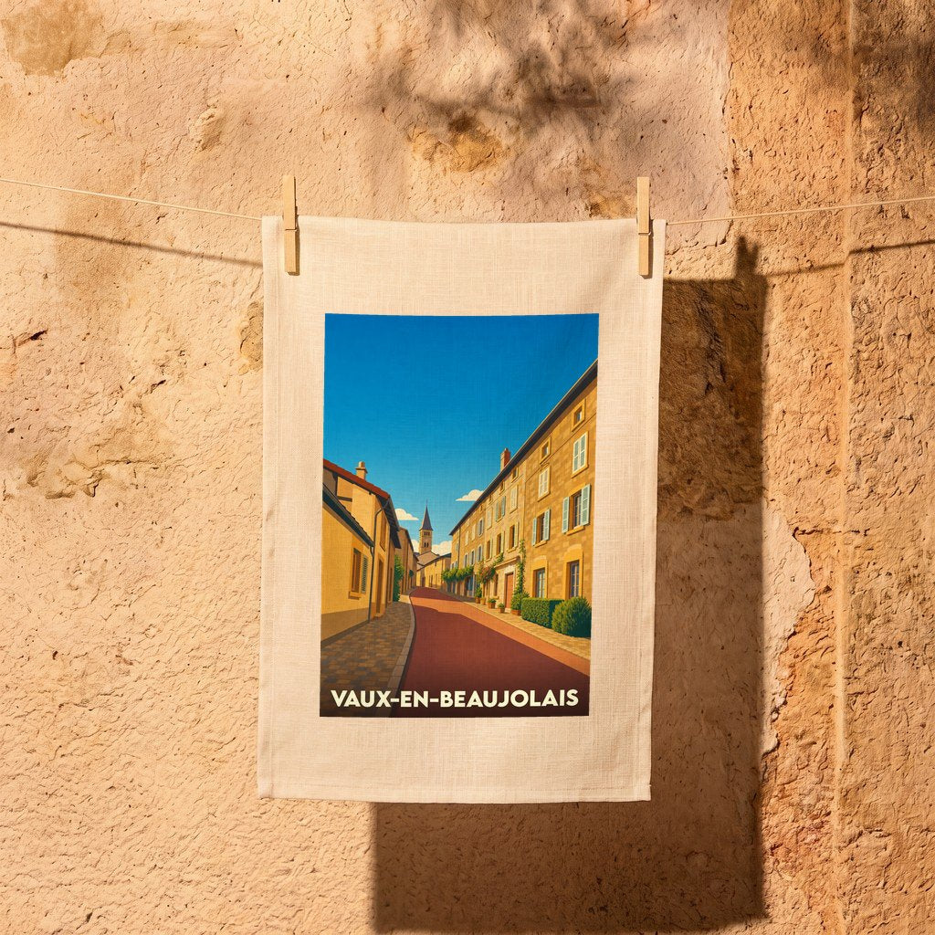 Torchon souvenir de la ville de Vaux-en-Beaujolais avec une illustration stylisée d'une rue pittoresque.