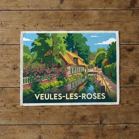 Torchon souvenir de la ville de Veules-les-Roses avec une illustration stylisée d'une maison fleurie au bord de l'eau.
