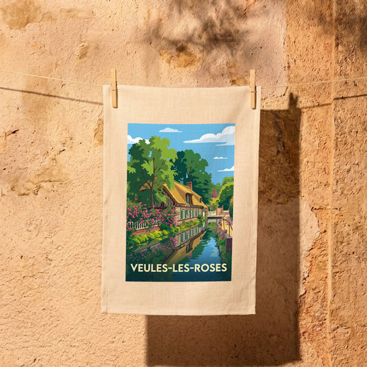 Torchon souvenir de la ville de Veules-les-Roses avec une illustration stylisée d'une maison fleurie au bord de l'eau.