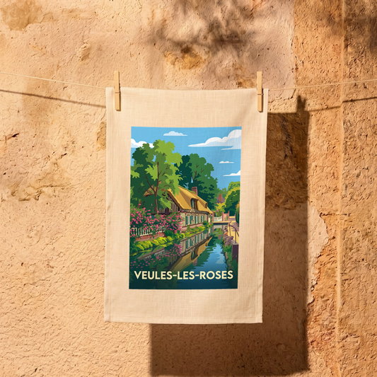 Torchon souvenir de la ville de Veules-les-Roses avec une illustration stylisée d'une maison fleurie au bord de l'eau.
