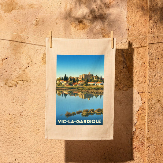 Torchon souvenir de la ville de Vic-la-Gardiole avec une illustration stylisée du village se reflétant dans l'eau.