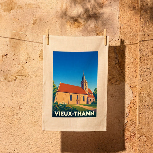 Torchon souvenir de la ville de Vieux-Thann avec une illustration stylisée d'une église sous un ciel bleu.