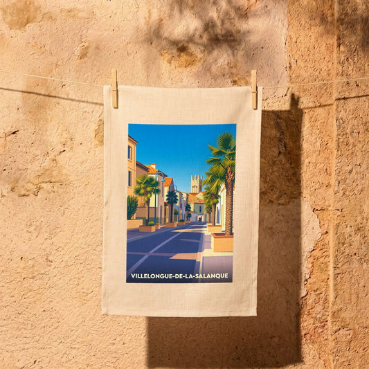 Torchon souvenir de la ville de Villelongue-de-la-Salanque avec une illustration stylisée d'une rue ensoleillée bordée de palmiers.