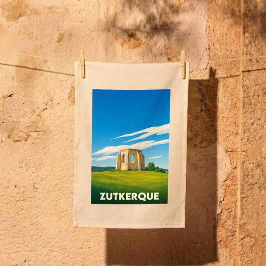 Torchon souvenir de la ville de Zutkerque illustré d'une ruine historique dans un paysage champêtre.