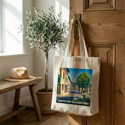 Tote bag souvenir de la ville de Sainte-Foy-l'Argentière avec une illustration stylisée d'une rue ensoleillée.